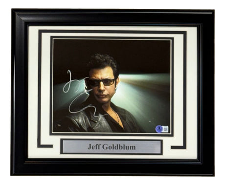 A Sports Integrity framed 8x10 photo of Jeff Goldblum from Jurassic Park, signed and authenticated by BAS, features him in sunglasses and a black leather jacket with dramatic lighting.