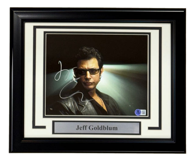 A Sports Integrity framed 8x10 photo of Jeff Goldblum from Jurassic Park, signed and authenticated by BAS, features him in sunglasses and a black leather jacket with dramatic lighting.
