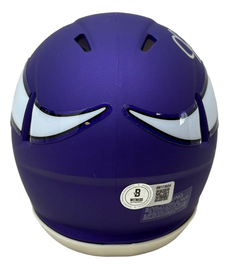 The Justin Jefferson Signed Minnesota Vikings Mini Speed Helmet by Sports Integrity features a purple design with white and black stylized eyes on the back and a certification sticker near the bottom, and comes with a display case.
