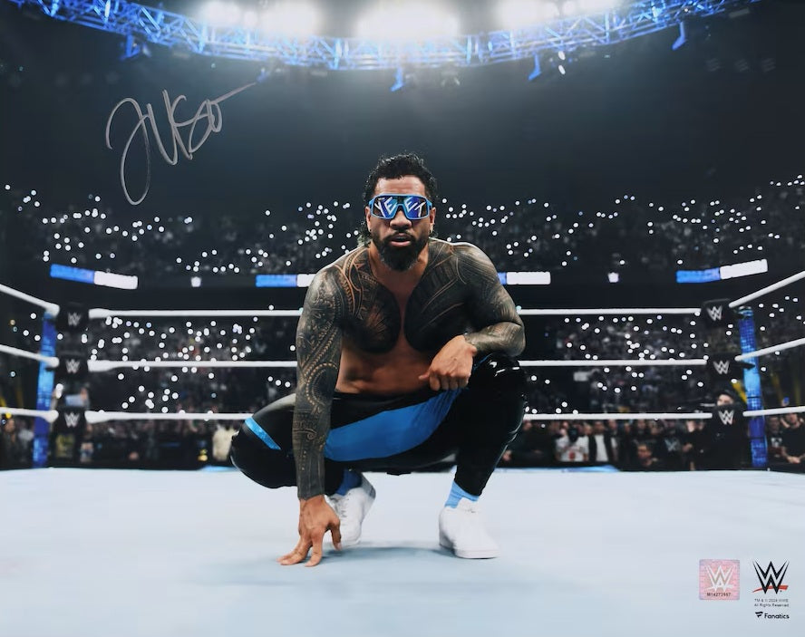 The Sports Integrity Jey Uso Signed 16x20 WWE Kneeling Photo shows Jey Uso in the ring, surrounded by cheering fans with lit phones in a bright arena—a must-have for WWE collectors.