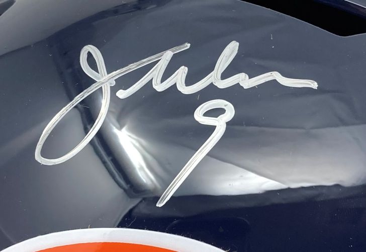 A white "9" signature is displayed on a dark glossy Chicago Bears helmet, with an orange and white accent visible. This is the Jim McMahon Signed Full Size Replica Speed Helmet by Sports Integrity.