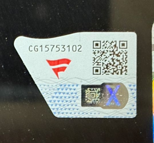 A close-up of a security sticker with a QR code, serial number CG15753102, red logo, patterned background, and an X-shaped hologram on a Joe Burrow Signed Framed 16x20 Bengals Orange Jersey Photo by Sports Integrity.