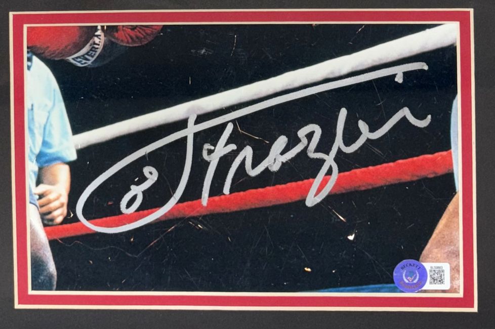 A close-up of the Sports Integrity Joe Frazier Signed Framed Cut Signature with an 8x10 photo vs Muhammad Ali, featuring a boxing ring and a bold silver autograph across the image.