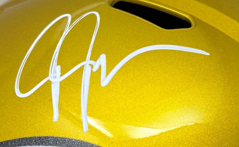 Close-up of a Justin Jefferson Signed Minnesota Vikings FS Flash Replica Speed Helmet by Sports Integrity, showcasing a bold white autograph on the shiny gold surface and a black vent near the top.