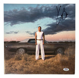 A man in a white sleeveless shirt and pants stands before a vintage car at sunset on the Kane Brown Signed The High Road Vinyl Record Cover by Sports Integrity, authenticated by PSA/DNA, with his signature above.