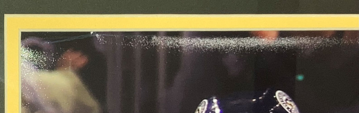 Close-up of mist spraying above a blue helmet with white emblems, set against a dark background with blurred people, from the Kris Letang Signed Framed 16x20 Pittsburgh Penguins Photo (Sports Integrity, JSA authenticated).