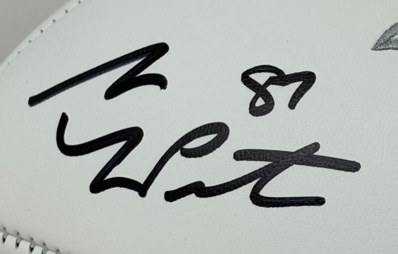 A Sam LaPorta Signed Detroit Lions Logo Football by Sports Integrity is shown up close, displaying a bold black signature and the number 87. The football comes with a BAS ITP certificate and includes a display case.