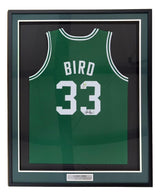 A Larry Bird Boston Signed Framed Green Basketball Jersey by Sports Integrity, featuring "BIRD" and #33 in white, an autograph, PSA/DNA authentication, a metal "Larry Bird" plaque, and a green/black mat border.