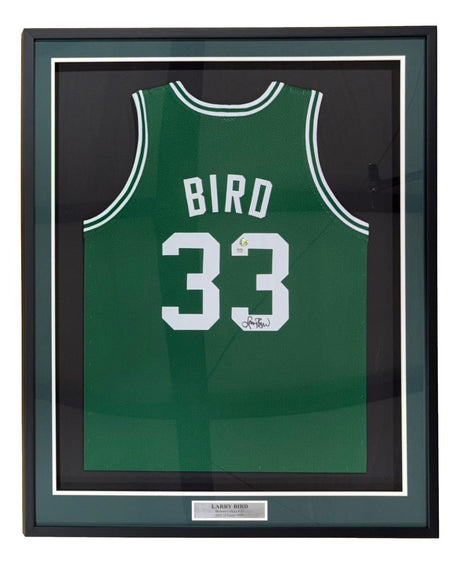 A Larry Bird Boston Signed Framed Green Basketball Jersey by Sports Integrity, featuring "BIRD" and #33 in white, an autograph, PSA/DNA authentication, a metal "Larry Bird" plaque, and a green/black mat border.