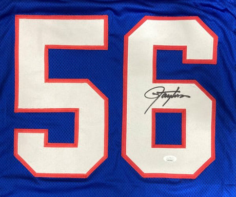 The Lawrence Taylor New York Signed Blue Football Jersey by Sports Integrity features bold white and red 56 on the front, with Taylor’s black ink signature on the right side of the 6 and an official JSA hologram.