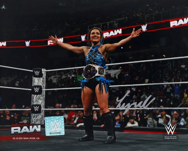 A smiling Lyra Valkyria stands center ring in WWE gear, arms outstretched with a championship belt, as spectators cheer. This signed 8x10 WWE photo is available from Sports Integrity via Fanatics.