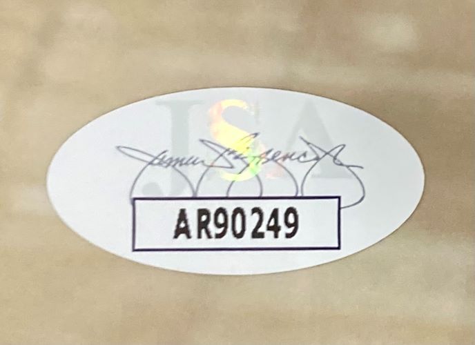 A Manu Ginobili Signed Framed 16x20 San Antonio Spurs Photo by Sports Integrity features an oval sticker with the code AR90249 in bold black letters and a faint JSA watermark with a cursive signature on a light brown surface.