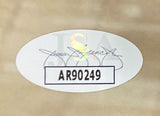A Manu Ginobili Signed Framed 16x20 San Antonio Spurs Photo by Sports Integrity features an oval sticker with the code AR90249 in bold black letters and a faint JSA watermark with a cursive signature on a light brown surface.