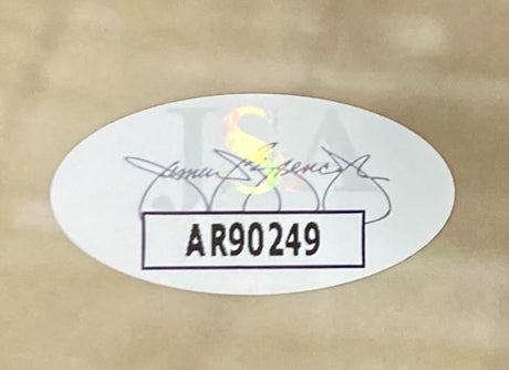 A Manu Ginobili Signed Framed 16x20 San Antonio Spurs Photo by Sports Integrity features an oval sticker with the code AR90249 in bold black letters and a faint JSA watermark with a cursive signature on a light brown surface.