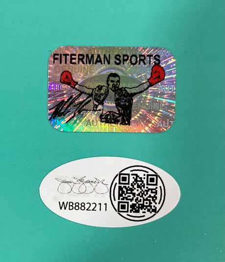 A holographic Sports Integrity sticker showing a boxer with red gloves is above an oval with a signature, QR code, and code WB882211 on teal, authenticating the Mike Tyson Signed 16x20 Boxing Punch Out Photo JSA QR Hologram.