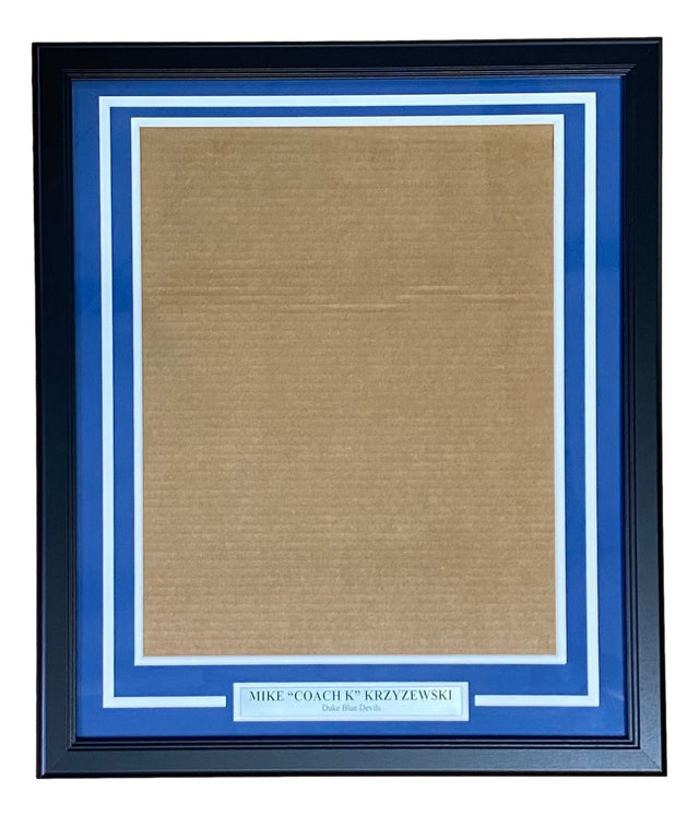 The Sports Integrity Coach K Mike Krzyzewski Duke 16x20 Vertical Photo Frame Kit features a black frame with blue and white matting and a plaque at the bottom that reads: MIKE COACH K KRZYZEWSKI Duke Blue Devils.