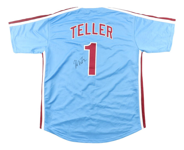 The Sports Integrity Miles Teller Philadelphia Signed Light Blue Baseball Jersey (BAS BT57636) features red and white trim, TELLER and number 1 on the back in white with a red outline, plus an autograph below the number.