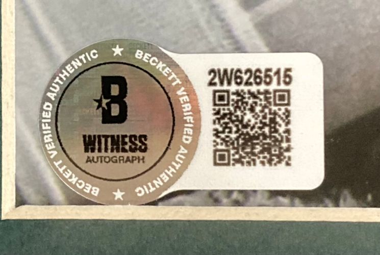 Close-up of a Beckett Witness Autograph sticker with logo, QR code, and code 2W626515 on a framed Milton Williams Signed 16x20 Eagles SB 59 Strip Sack Spotlight Photo by Sports Integrity. Text: Beckett Verified Authentic.