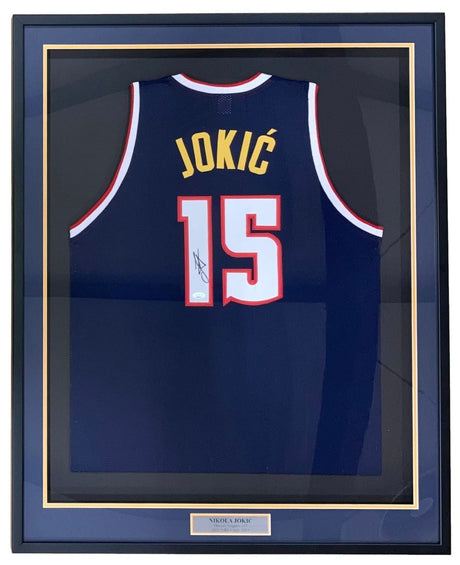 The Sports Integrity Nikola Jokic Denver Signed Framed Navy Blue Basketball Jersey (JSA) features "JOKIĆ" and number 15, autographed and displayed behind glass with a nameplate at the bottom.
