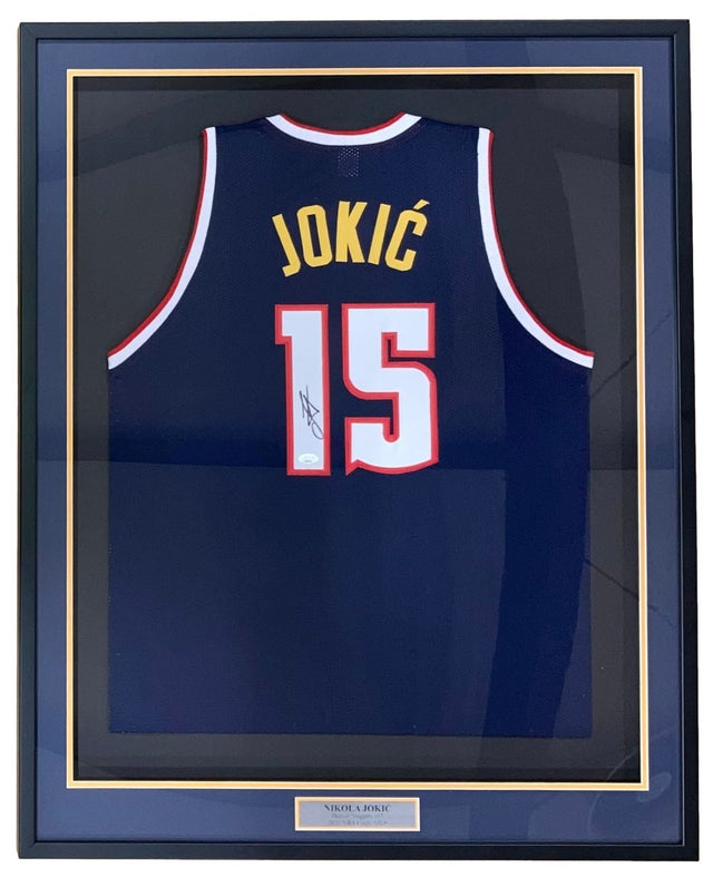 The Sports Integrity Nikola Jokic Denver Signed Framed Navy Blue Basketball Jersey (JSA) features "JOKIĆ" and number 15, autographed and displayed behind glass with a nameplate at the bottom.