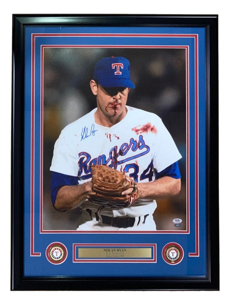 Sports Integrity's Nolan Ryan Signed Framed 16x20 Texas Rangers Bloody Lip Photo (PSA/DNA) features the legendary pitcher in a white uniform and blue cap, holding a glove, with his autograph and team logos included.