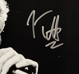 The Sports Integrity Joe Elliott Signed 11x14 Black and White Def Leppard Photo (JSA ITP) features a close-up of a hand holding a microphone, with Joe Elliott's large silver autograph across the image. The person's face is partially out of view.