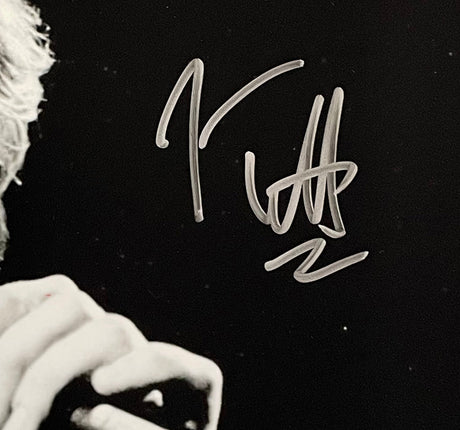 The Sports Integrity Joe Elliott Signed 11x14 Black and White Def Leppard Photo (JSA ITP) features a close-up of a hand holding a microphone, with Joe Elliott's large silver autograph across the image. The person's face is partially out of view.