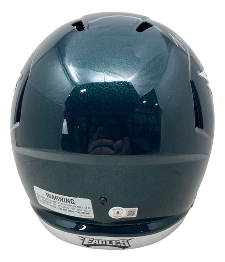 The Randall Cunningham Signed Philadelphia Eagles FS Speed Replica Helmet by Sports Integrity is a glossy, dark green helmet featuring a white warning label, certification sticker, and "EAGLES" on the lower edge.
