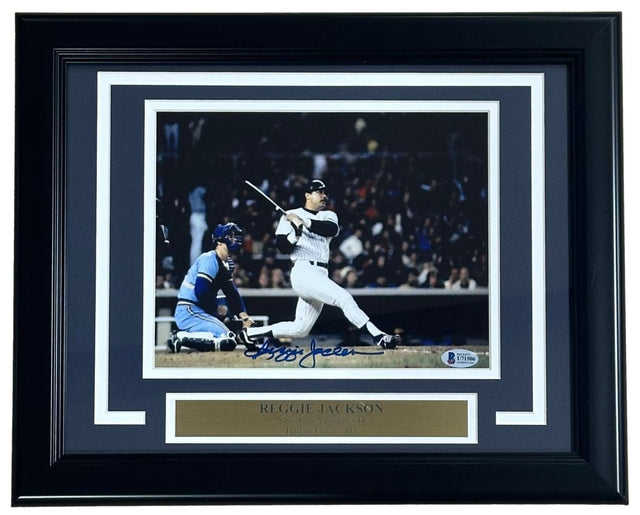 Sports Integrity Reggie Jackson Signed Framed 8x10 Photo shows him batting in the 1981 ALDS for the Yankees, with a catcher in blue gear behind. Includes a name plaque and BAS authentication.