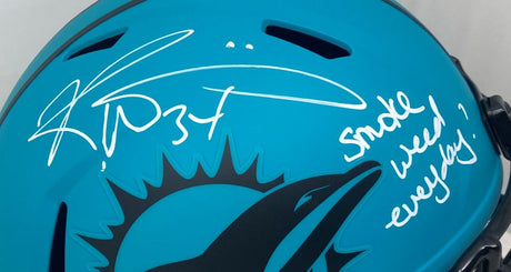 The Sports Integrity Ricky Williams Signed Dolphins FS Rave Speed Replica Helmet features a teal Miami helmet with black dolphin logo, signed in white marker with "Smoke Everyday" and an autograph.