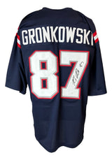 The Sports Integrity Rob Gronkowski New England Signed Alternate Blue Football Jersey (JSA Hologram) is a navy blue, short-sleeve jersey with red and white stripes, featuring “GRONKOWSKI” and #87 in white/red, autographed on the number.