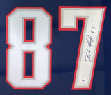 A close-up of the Rob Gronkowski New England Signed Framed Blue Football Jersey by Sports Integrity, featuring a large white and red 87, Gronkowski's autograph on the 7, and a PSA/DNA certification sticker.