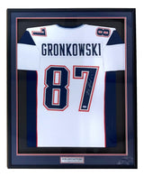 The Sports Integrity Rob Gronkowski New England signed framed white football jersey (#87) features his name, a PSA/DNA hologram, and is displayed in a black frame with a plaque at the bottom.