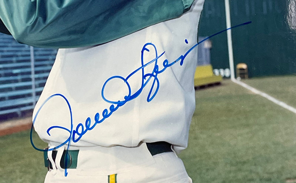 A signed 8x10 photo of Rollie Fingers in an Oakland Athletics uniform, featuring his large blue autograph. Offered by Sports Integrity, BAS 622 authenticated. Bleachers and part of a field appear in the background.