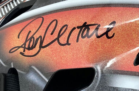 A close-up of a Ron Hextall Signed Philadelphia Flyers Full Size Replica Goalie Mask by Sports Integrity shows a bold black autograph curving above a vent on the orange and silver helmet.