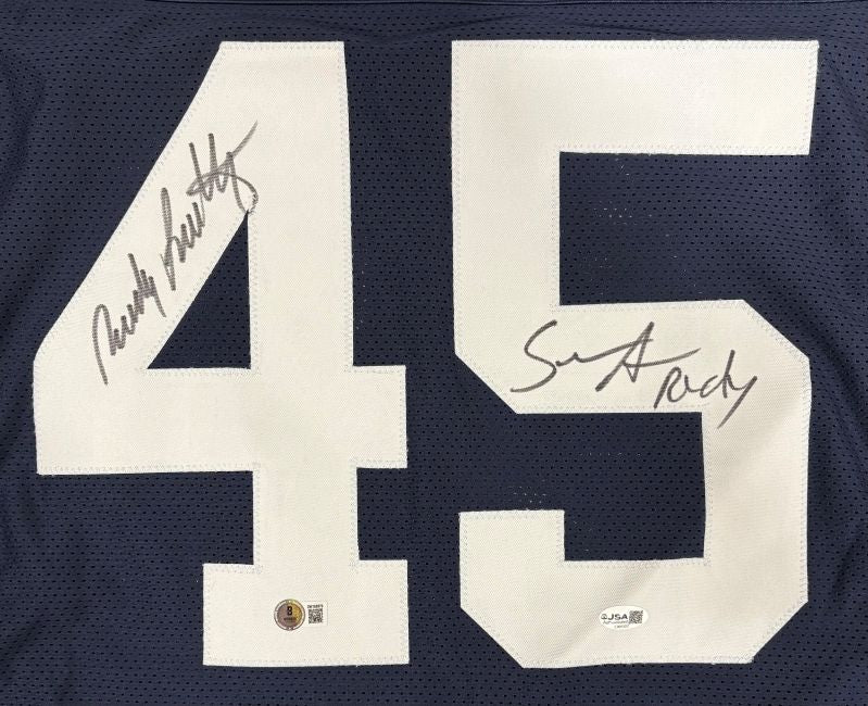 Sports Integrity Rudy Ruettiger Sean Astin Notre Dame Signed Blue "Never Quit" Jersey features a large white 45 with two black signatures, BAS+JSA certification stickers near the bottom.