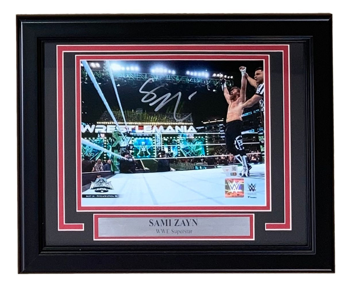 The Sports Integrity Sami Zayn Signed Framed 8x10 WWE Photo from Fanatics features the superstar celebrating in the ring, complete with a silver nameplate and WWE logo beneath the photo.
