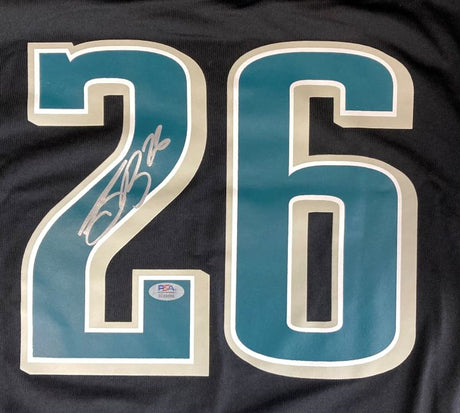 A close-up of the Saquon Barkley Signed Philadelphia Eagles Super Bowl 59 LIX Black Nike Jersey by Sports Integrity, featuring a large teal and white number 26 with Barkley's white autograph and a PSA authentication sticker.