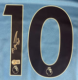 A close-up of a Sergio Aguero Signed Manchester City Puma Soccer Jersey by Sports Integrity, showing a large black number 10 outlined in white, the Premier League lion logo, Aguero's signature, and an authenticity sticker.