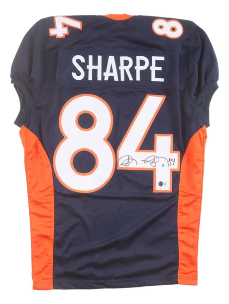 The Sports Integrity Shannon Sharpe Denver Signed Navy Pro-Cut Football Jersey BAS features “SHARPE” and number 84 in white and orange, with an autographed number.