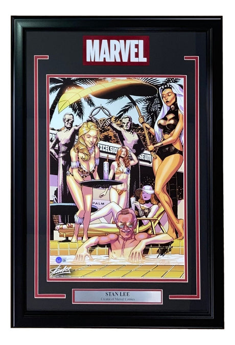 The Sports Integrity Stan Lee Signed Framed 13x19 JJ Kirby Photo features Marvel women in bikinis poolside with palm trees and a MARVEL sign. In the foreground, Stan Lee, smiling in the pool, is identified by a plaque. BAS LOA included.