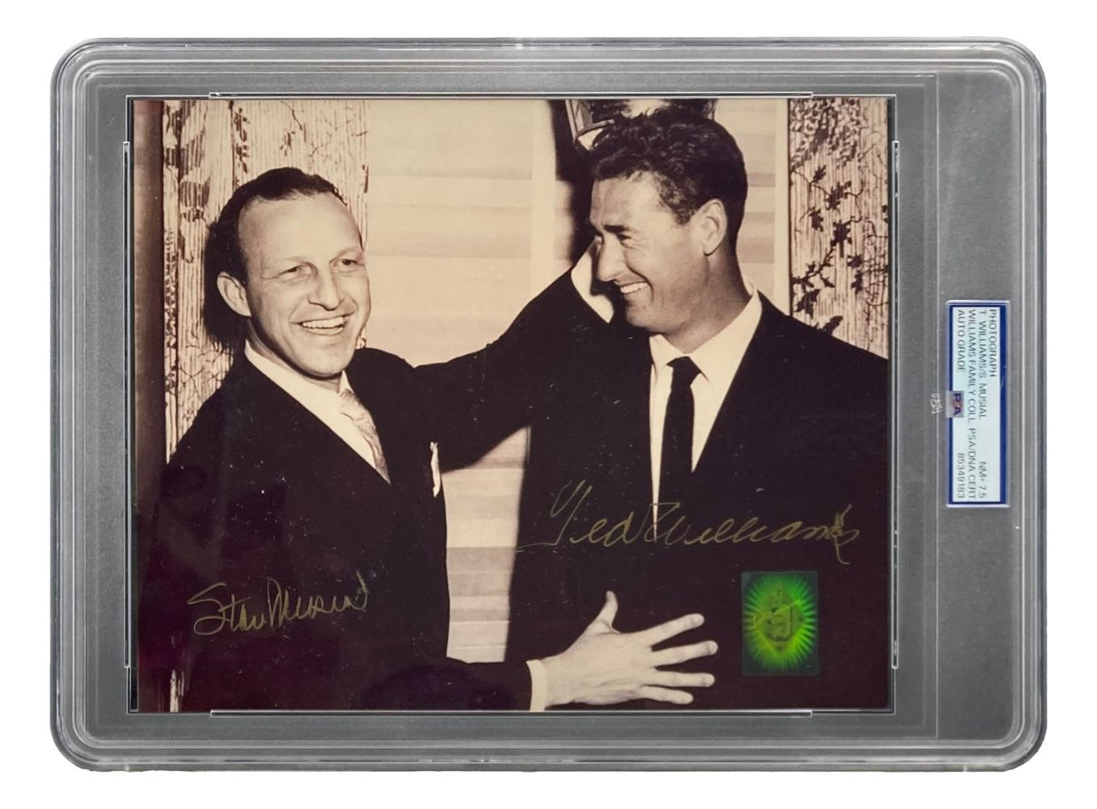 Ted Williams and Stan Musial, both in suits, smile and pose together indoors on this autographed 8x10 photo. Encased with a PSA NM-MT 7.5 label, the piece is offered by Sports Integrity. Patterned curtains appear in the background.
