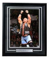 The Sports Integrity Stone Cold Steve Austin Signed Autographed Framed 16x20 WWE Photo BAS features the wrestler in the ring, arms raised, wearing a black vest and blue shorts, with cheering fans and signs in the background.