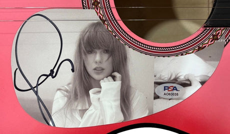 This Taylor Swift Signed 38" Tortured Poets Department Pink Acoustic Guitar from Sports Integrity features her black signature, a black-and-white photo of Taylor with long hair and bangs, and PSA authentication sticker AO63035.