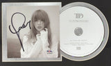 A Taylor Swift Signed Framed Insert with an 8x10 concert stadium photo, authenticated by PSA/DNA, from Sports Integrity is displayed alongside The Manuscript CD featuring the album title and artist’s name in simple black text.
