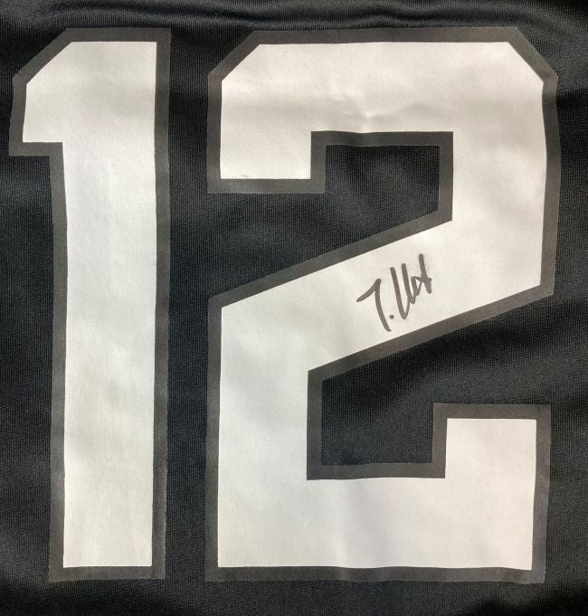 A close-up of a Travis Hunter Signed Jacksonville Jaguars Black Nike Game Replica Jersey by Sports Integrity, featuring a large white number 12 outlined in gray and a black ink signature on the number 2.