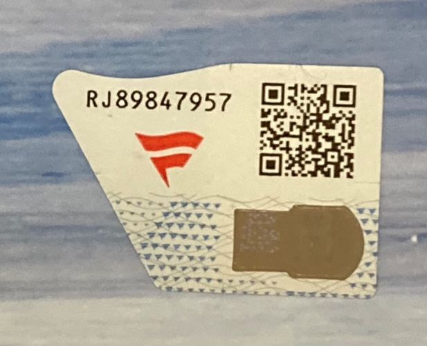 A Sports Integrity sticker with code RJ89847957 is on the Trish Stratus Signed Framed 8x10 WWE Photo (Fanatics), featuring a red and white logo, QR code, and metallic strip on a blue and white patterned background.