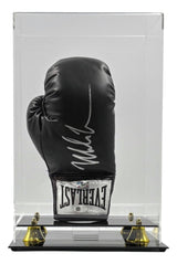 A Mike Tyson signed black Everlast right-hand boxing glove is displayed upright in a clear vertical acrylic case with gold corners and mirrored base by Sports Integrity. Authenticated by JSA QR.